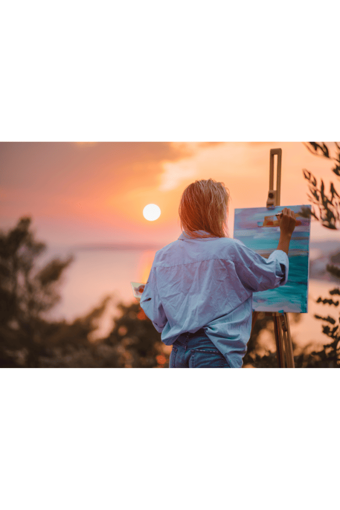 woman painting looking into sunset
