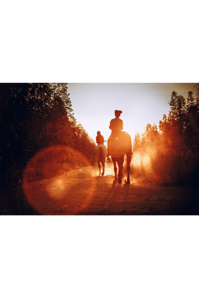 woman on horseback riding into sunset