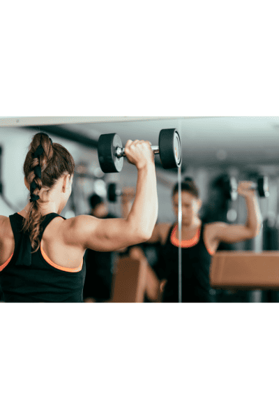 how to achieve wellness? Start with exercise - woman doing weights as an exercise in the gym