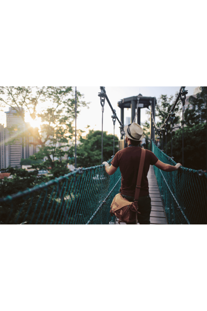 man crossing bridge though jungle